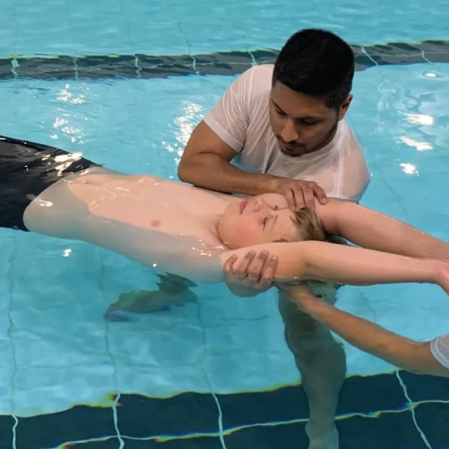 Photo of two people holding a child floating in the pool