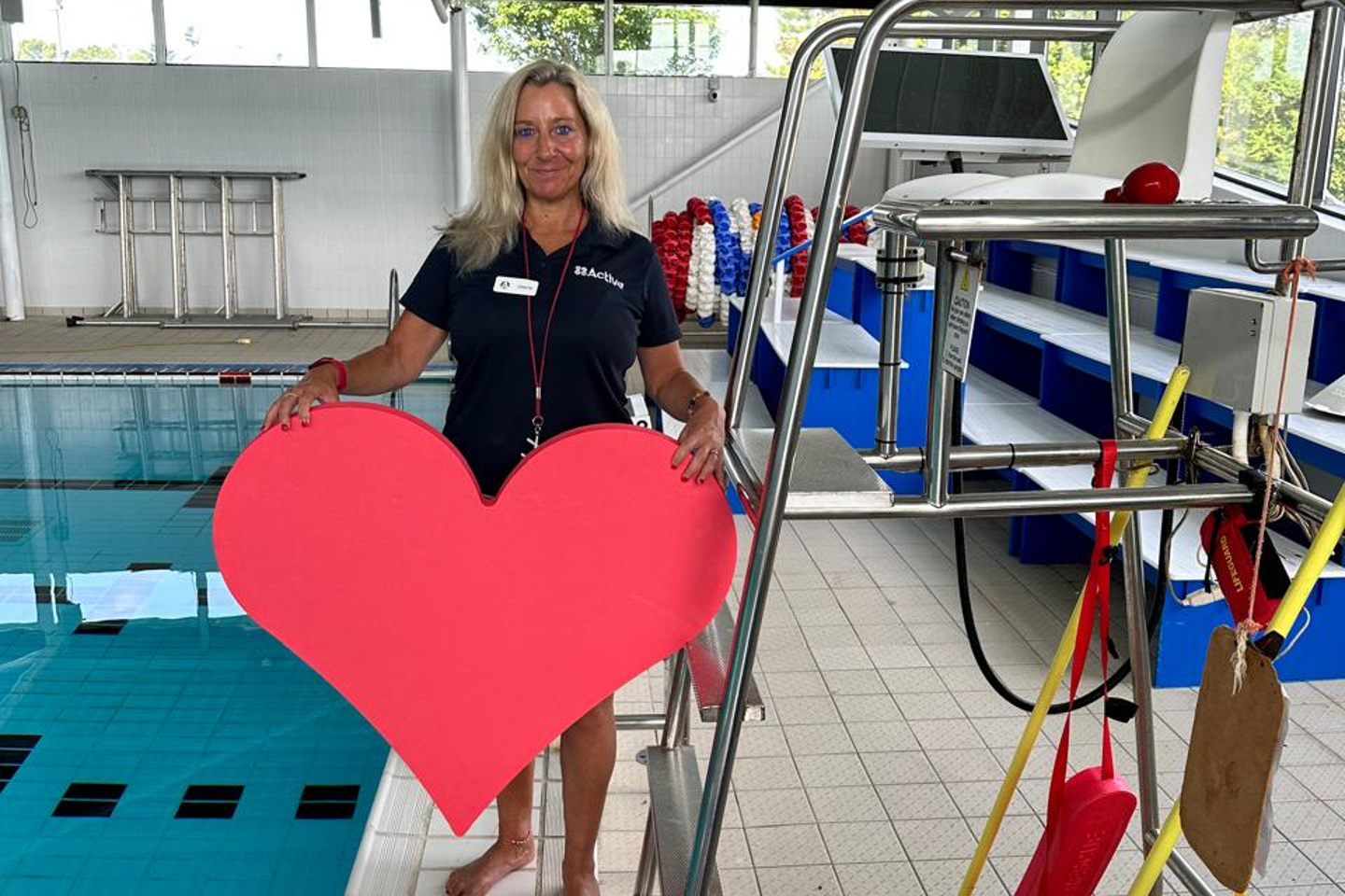 Photo of lifeguard at Les Quennevais Sports Centre holding a giant hear shaped float near the pool