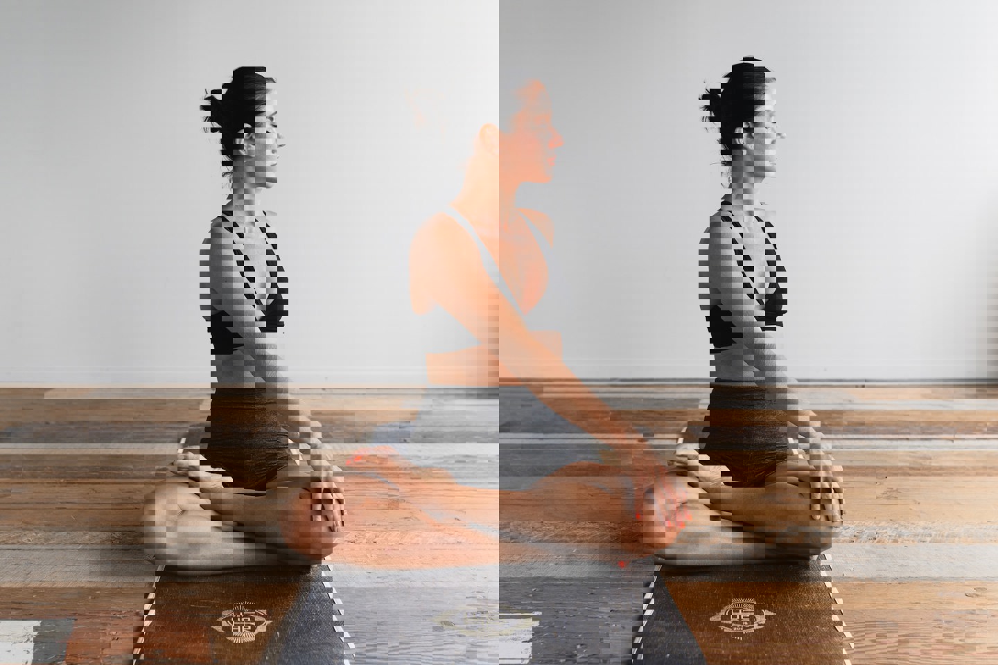 Photo of a person sat on a mat on the floor stretching to one side