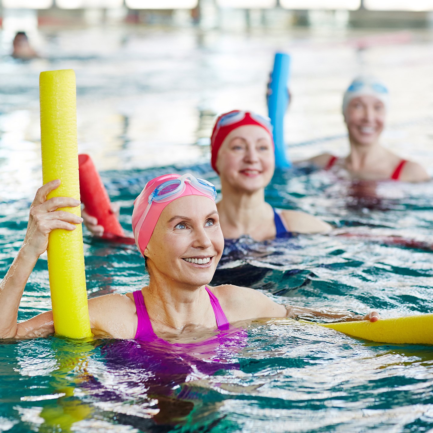 Adults in swimming lesson using pool float