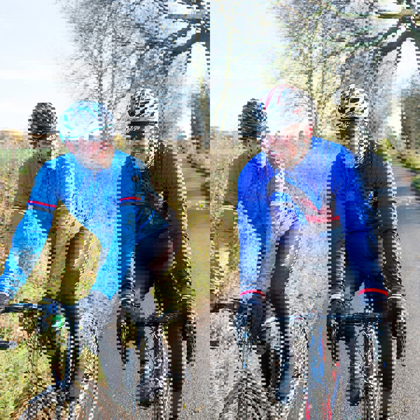 Two men cycling while wearing appropriate cycling clothing and helmets