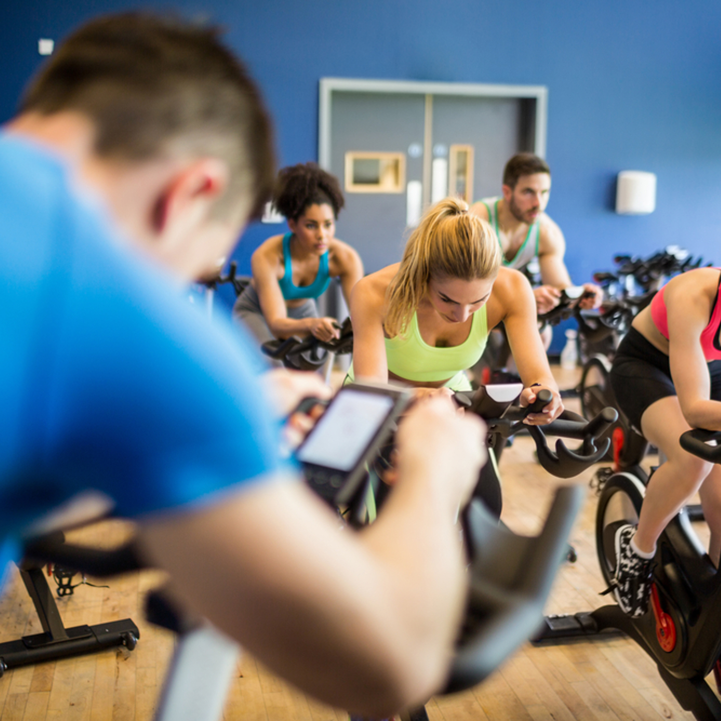 Photo of a spin class looking from behind the class instructor towards the group of people in the class