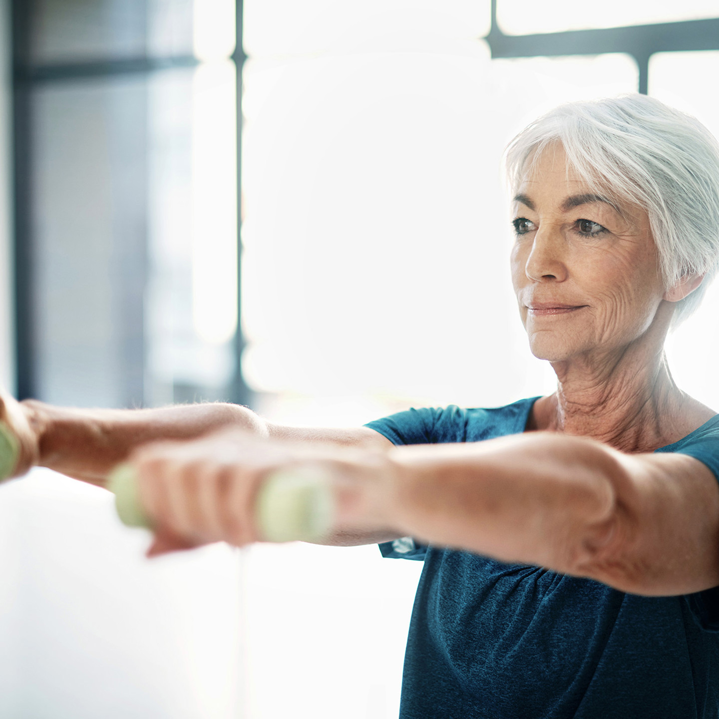 Old lady lifting dumbbells at the gym