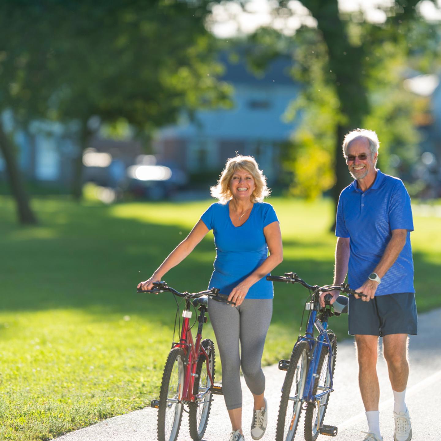 Photo of two people walking on a path with their bikes