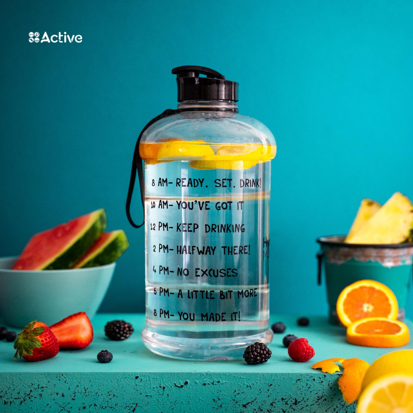Photo of a large bottle of water with timings to help you drink more water surrounded by fruit